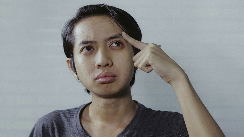 A man holding his finger to his head, thinking